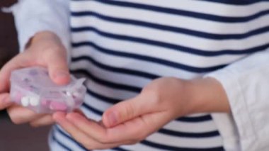 Kadın ellerinin ilaçlarını sınıflandırırken odaklanmış arka planı haftalık tıbbi hap kutularını günlük haplarla kapatıyorlar beyaz pembe haplar ve kapsüllerle ilaç alıyorlar. Genç kadın.