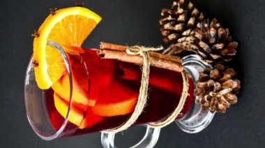Dikey Noel şarabını baharatlı ve portakallı koyu siyah arka planda yakınlaştır. Seçici odaklanma. Anason yıldızları ve tarçın çubukları. Noel konileri. Sonbahar konsepti