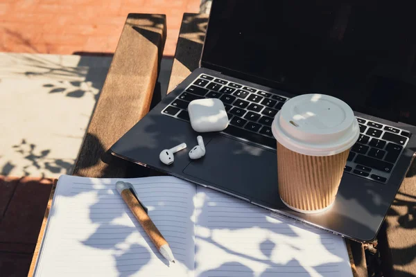 Take away coffee in craft recycling paper cup with paper notebook laptop with wireless headphones. Mockup Coffee break. Audio healing, sound therapy wellness rituals, positive mental health habits listening podcast writing self discovery gratitude jo