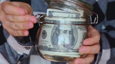 Dollar banknote saving money in glass jar. Unrecognizable woman moderate consumption and economy Collecting money. Tips. Business, finance, saving, banking and people concept. Extra money, passive