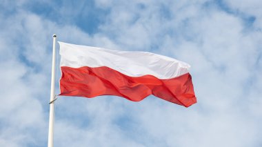 Güzel mavi gökyüzüne doğru dalgalanan Polonya bayrağı. Polonya bayrağı mavi gökyüzünde beyaz ve kırmızı dalgalanıyor. Polonya 'nın ulusal bayrağı bayrak direğinde dalgalanıyor.