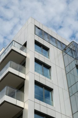 Gökyüzü arka planında cam cepheli modern ofis binası. Sarı süslemeli şeffaf cam ofis duvarı. Modern Avrupa binasının dış cephesi