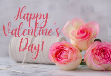 Delicate pink roses with spool of white cotton rope. Minimal trendy composition. Romantic pastel pink rose flowers. Greeting card for Happy VALENTINES Day text holiday backdrop