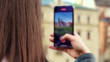 Female traveler in historical places looks around courtyard of landmark and shoots short video on phone. Tourist photographs historic place on sunny day. Unrecognizable woman Tourism and blogging