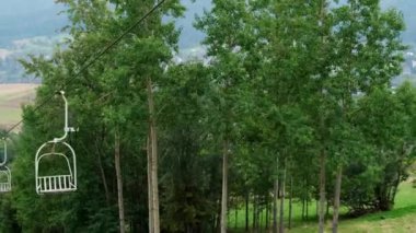 Chair lift with view of autumn mountains. Cable chair ski lift in Zakopane mountain resort Poland. Scenic autumn landscape. Ropeway, empty ski lift chairs Moving ski lifts or funiculars on the