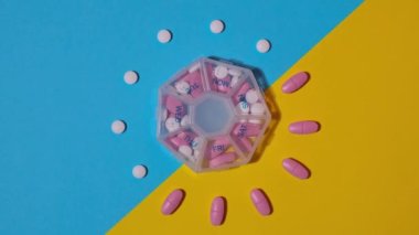 Organizer weekly shots of medical pill box with doses of tablets for daily take medicine with white pink drugs and capsules. Vitamins at home. Medication dietary supplements, immunity and disease