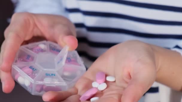 女性の手の並べ替え薬オーガナイザー毎週のショット白いピンクの薬やカプセルと毎日の服用薬の錠剤の用量で医療用錠剤ボックスの閉鎖 若いです女性取得彼女の毎日ビタミン — ストック動画