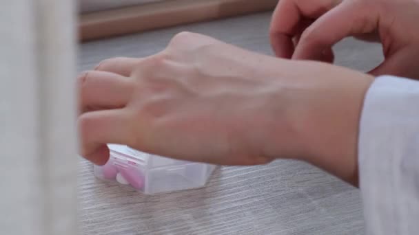 女用手分选药丸组织者每周拍摄一次医用药丸盒闭塞 每日服用含有白色粉红药物和胶囊的药丸片 年轻女人每天都吃维生素 — 图库视频影像
