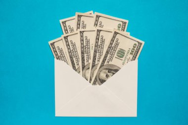 Dollar banknote saving money in envelope on blue background copy space. Consumption and economy Collecting money. Tips. Business, finance, saving, banking and people concept. Extra money, passive income. Saving for travel, crisis, house, car, educati
