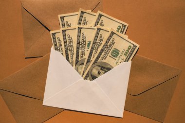 Dollar banknote saving money in envelope on beige background copy space. Consumption and economy Collecting money. Tips. Business, finance, saving, banking and people concept. Extra money, passive income. Saving for travel, crisis, house, car, educat