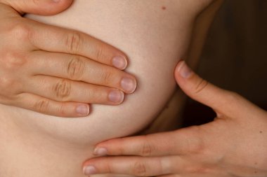 Tanınmayan kadınlar üstsüz göğüs kanseri kontrolü yapıyorlar. Göğüs kanseri kontrolü, sağlıklı yaşam tarzı konsepti. Genç ve güzel bir kadın, göğsünde yumru ya da meme kanseri belirtileri var mı diye bakıyor.