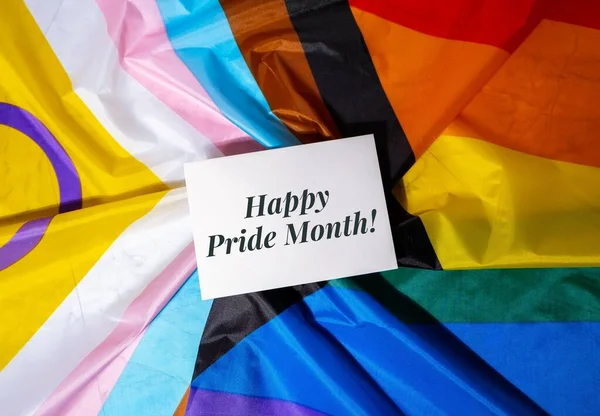 HAPPY PRIDE MONTH inscription positive quote phrase Greeting card on Rainbow LGBTQIA flag made from silk material. Symbol of LGBTQ pride month. Equal rights. Peace and freedom. Support LGBTQIA community. Diversity equality