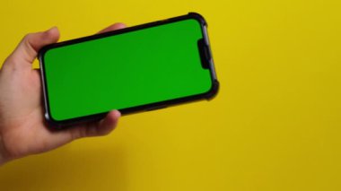 Sarı arka planda yeşil ekranlı cep telefonu. Krom anahtar. Model yap. Ürününüz için cep telefonu modeli. Teknoloji cep telefonu mobil uygulaması. Uygulamalar 4k görüntüsü 