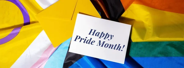 HAPPY PRIDE MONTH text on postcard inscription positive quote phrase Greeting card on Rainbow LGBTQIA flag made from silk material. Symbol of LGBTQ pride month. Equal rights. Peace and freedom. Support LGBTQIA community. Diversity equality