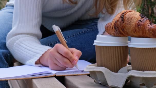 Estudiante Joven Con Cuaderno Parque Beber Café Comer Croissants Escribir — Vídeo de stock