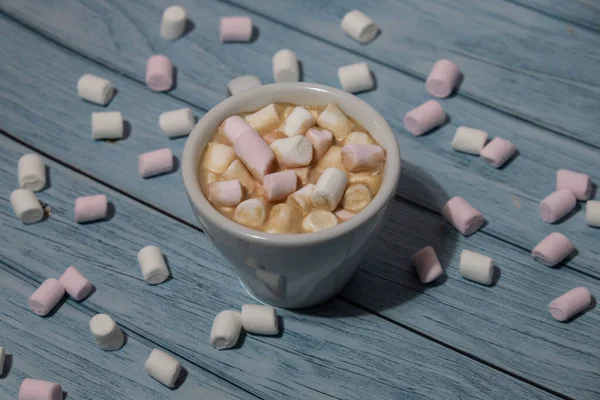 Close up of Cup hot chocolate marshmallows cacao. Cozy Coffee with marshmallows on wooden blue background. Copy space for text. Wallpaper design. Sweet unhealthy food 
