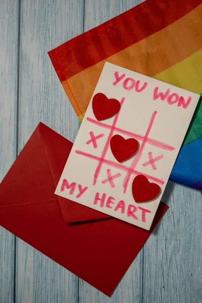 Handmade valentine with Text YOU WON MY HEART and tic tac toe game red envelope and LGBTQ flag. Gift idea with your own hands. Diversity equality