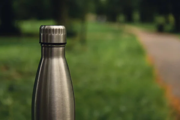 Water bottle. Reusable steel thermo water bottle on green grass. Sustainable lifestyle. Plastic free zero waste free living. Go green Environment protection. Health-conscious. Steel thermo water