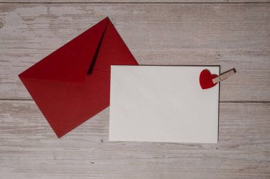 Greeting or invitation card mock up with red envelope on wooden background. Romantic Small hearts Valentine day. Blank paper card copy space for your text. Holiday morning. Top view, flat lay