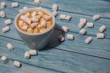 Close up of Cup hot chocolate marshmallows cacao. Cozy Coffee with marshmallows on wooden blue background. Copy space for text. Wallpaper design. Sweet unhealthy food 