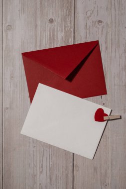 Greeting or invitation card mock up with red envelope on wooden background. Romantic Small hearts Valentine day. Blank paper card copy space for your text. Holiday morning. Top view, flat lay minimalist aesthetic luxury bohemian business branding con