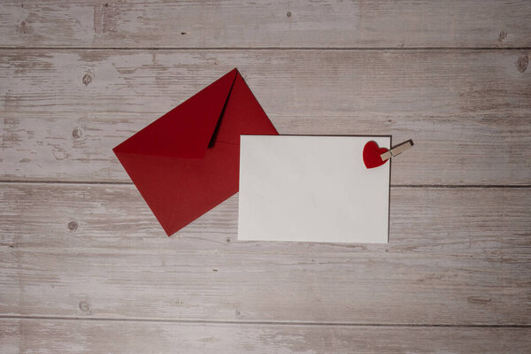 Greeting or invitation card mock up with red envelope on wooden background. Romantic Small hearts Valentine day. Blank paper card copy space for your text. Holiday morning. Top view, flat lay minimalist aesthetic luxury bohemian business branding con