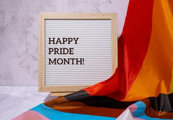 HAPPY PRIDE MONTH inscription positive quote phrase text frame on Rainbow LGBTQIA flag made from silk material. Symbol of LGBTQ pride month. Equal rights. Peace and freedom. Support LGBTQIA community. Diversity equality