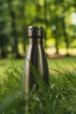 Water bottle. Reusable steel thermo water bottle on green grass. Sustainable lifestyle. Plastic free zero waste free living. Go green Environment protection. Health-conscious. Steel thermo water bottle of silver on background of blurred grass. 