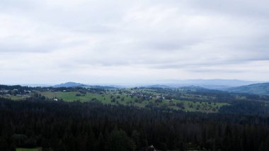 Aerial view of Zakopane town underneath Tatra Mountains taken from the Gubalowka mountain range. Drone High mountains and green hills in summer or spring. Scenic mountain view in Poland. Travel tourist destinations