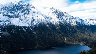 Czarny Staw pod Rysamy or Black Pond lake near the Morskie Oko Snowy Mountain Hut in Polish Tatry mountains, drone view, Zakopane, Poland. Aerial view shot of beautiful green hills and mountains in dark clouds and reflection on the lake Morskie Oko l