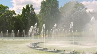 Multimedia Fountain Park in Warsaw, Poland in daytime. Fountains near the royal castle in Warsaw. Fountains multimedia park in Warsaw. Sunny summer day with blue sky and green trees