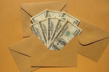 Dollar banknote saving money in envelope on beige background copy space. Consumption and economy Collecting money. Tips. Business, finance, saving, banking and people concept. Extra money, passive income. Saving for travel, crisis, house, car, educat