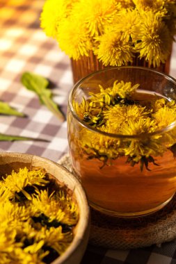 Dandelion flower healthy tea in glass cup on table. Herbal medicine Delicious tisane tea from with fresh yellow blossom dandelion flowers inside tea cup. Green clearing infusion Wildflowers Eco friendly organic brand concept. Nice greeting card for I
