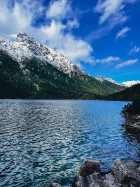 Morskie Oko lake Snowy Mountain Hut in Polish Tatry mountains, Zakopane, Poland. Beautiful green hills and mountains in dark clouds and reflection on the lake Morskie Oko lake. Travel tourist destination