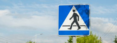 Bulutlu gökyüzünde yaya geçidinin dikey işareti, yaya geçidi. Dikkat dikkat. Açık havada.