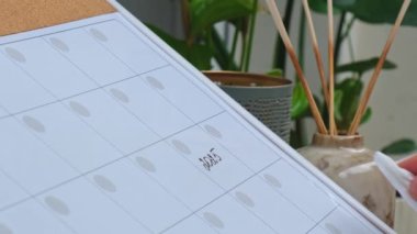 Female hand cleaning 2025 year and writing 2026 YEAR with marker on whiteboard. Change years Making appointment of event holiday Magnetic board with the days of the month. Place to enter important