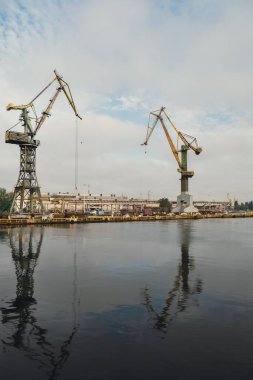 Motlawa river to Baltic Sea. Coal mine, polluting environment by the river POV from ferry swimming on river canal. Industrial building at the Gdansk Shipyard. Prefabrication workshop and heavy cranes