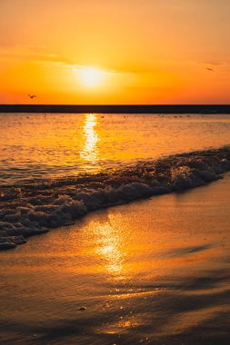 Güneş ışığının günbatımında deniz yüzeyine yansıması. Turuncu ve altın rengi mavi gökyüzü. Manzaralı altın deniz. Denizden dramatik sarı güneş geliyor. Muhteşem yaz manzarası