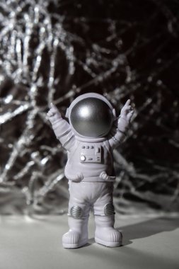 Plastic toy figure astronaut on silver background Copy space. Concept of out of earth travel, private spaceman commercial flights. Space missions and Sustainability
