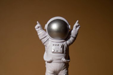 Plastic toy figure astronaut on beige neutral background Copy space. Concept of out of earth travel, private spaceman commercial flights. Space missions and Sustainability