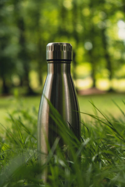 Water bottle. Reusable steel thermo water bottle on green grass. Sustainable lifestyle. Plastic free zero waste free living. Go green Environment protection. Health-conscious. Steel thermo water