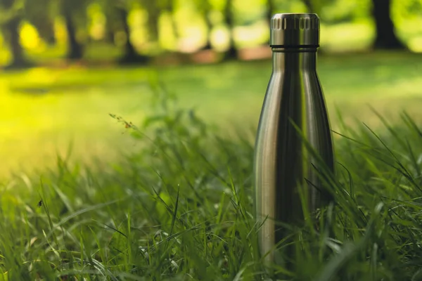 Water bottle. Reusable steel thermo water bottle on green grass. Sustainable lifestyle. Plastic free zero waste free living. Go green Environment protection. Health-conscious. Steel thermo water