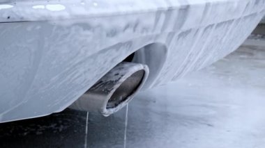 Washing luxury silver car on touchless car wash. Washing sedan car with foam self-service and high pressure water. Winter cleaning in car wash. Cleanliness and order in urban environment
