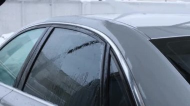 Washing luxury silver car on touchless car wash. Washing sedan car with foam self-service and high pressure water. Winter cleaning in car wash. Cleanliness and order in urban environment