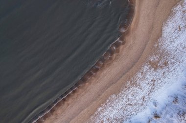 Gdansk 'taki soğuk Baltık deniz karlı plajında kış. Karla kaplı kumsalların ve kumulların havadan görünüşü ve insansız hava aracıyla yakalanan sakin deniz manzarası. Polonya 'da kış turizmi