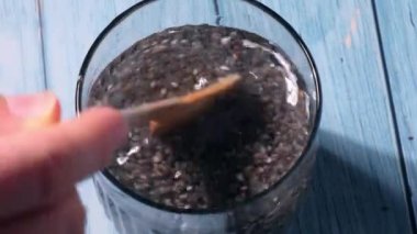 Preparing superfood water drink rich in Omega 3 fatty acids. Pouring coconut water. Adding soaked chia seeds and lemon detox Breakfast. Clean eating, weight loss, dieting food concept Vegetarian