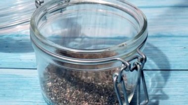 Slow motion chia seeds fall in glass jar. Healthy superfood rich in Omega 3 fatty acids. Dry healthy natural ingredient. Chia grains are falling. Vegetarian food 