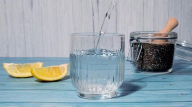 Preparing superfood water drink rich in Omega 3 fatty acids. Pouring coconut water. Adding soaked chia seeds and lemon detox Breakfast. Clean eating, weight loss, dieting food concept Vegetarian