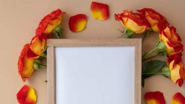 Mockup Wooden frame with Empty white paper blank and delicate red roses on beige background. Minimal trendy composition. Romantic pastel pink rose flowers. Neutral earth tones. Copy space Greeting