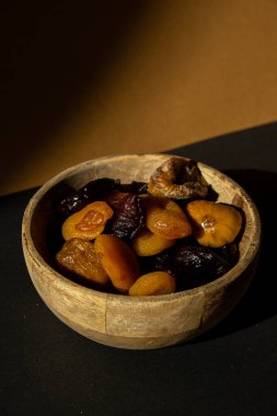 Eco wooden Bowl with different Mix dried fruits apricots prunes figs. Healthy food lifestyle. Vegan dessert snack. Creative shadows Isometric background